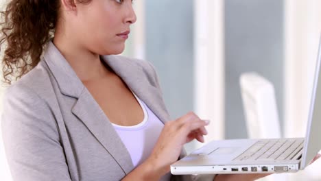 mujer de negocios embarazada usando su computadora portátil