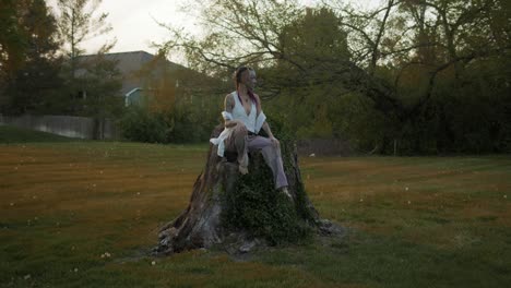 Celtic-Beltane-festival,-an-individual-sits-atop-a-felled-tree,-adorned-for-the-celebration,-evoking-the-spirit-of-this-Scottish-holiday