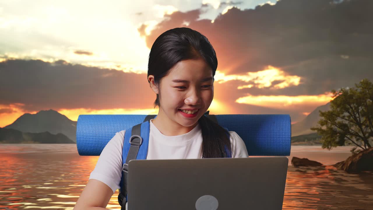 Woman Working on a Laptop by a Lakeside Sunset