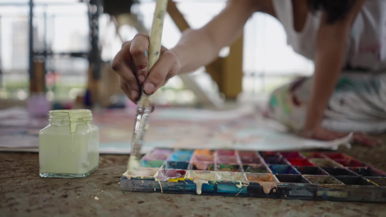Artist painting on the floor with watercolors
