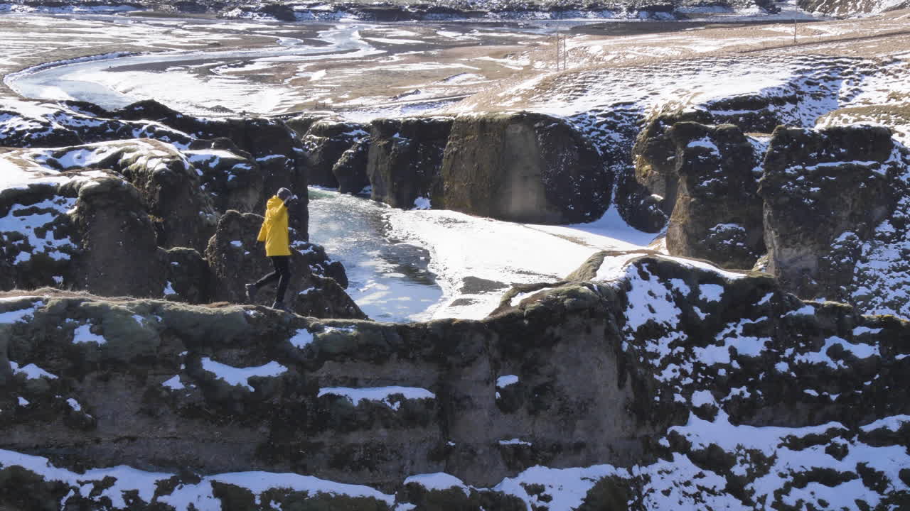 молодой путешественник идет по крутой тропе в каньоне фьядраргляфур зимой