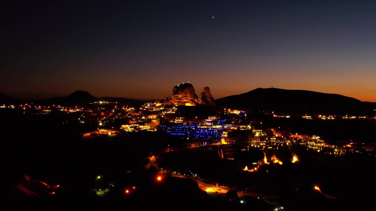 Capadócia à noite com luzes brilhantes e céu escuro
