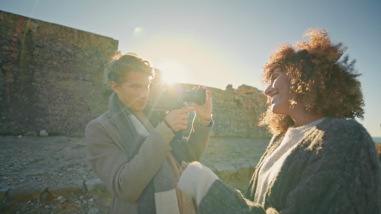 Curly lady posing photographer evening beach closeup. Blonde guy taking photos