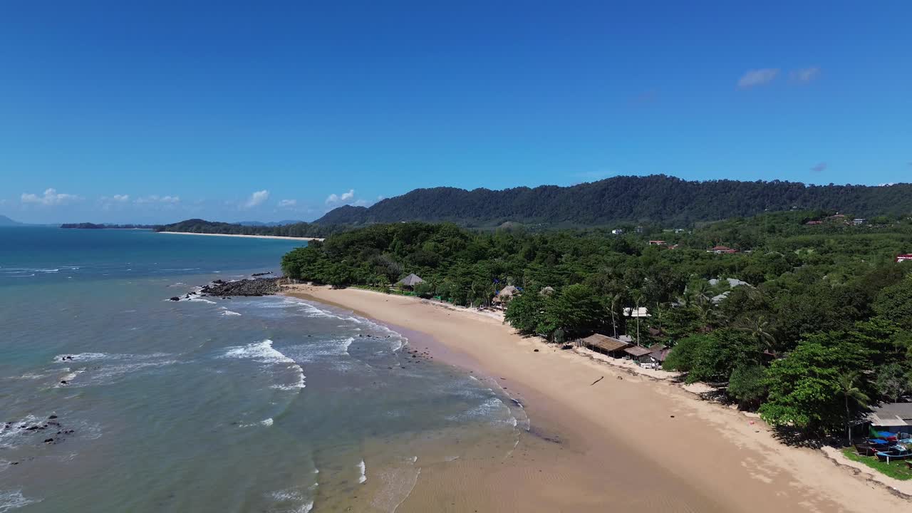 Filmato aereo realizzato con drone di bungalow su spiagge tropicali lungo la spiaggia sabbiosa con acqua turchese. Isola di Koh Lanta in Thailandia con palme, piccole imbarcazioni, spiagge sabbiose e acqua cristallina turchese