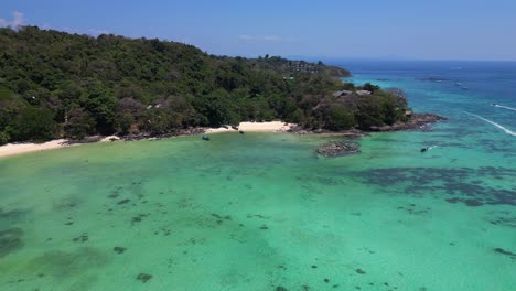 Aerial-view-of-a-tropical-island-beach-with-turquoise-water-showing-long-tail-boats-waiting-for-tourists-in-thailand