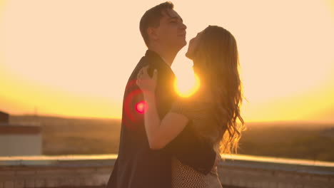 dos amantes abrazándose bailando en la parte superior de un rascacielos con vistas a la ciudad al amanecer y al atardecer.