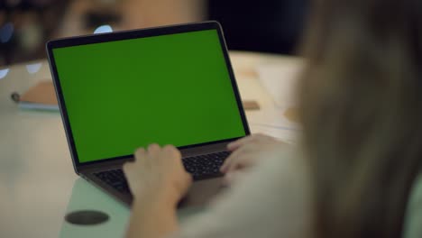 Woman-hand-typing-keyboard-of-laptop-computer-with-green-screen-at-home