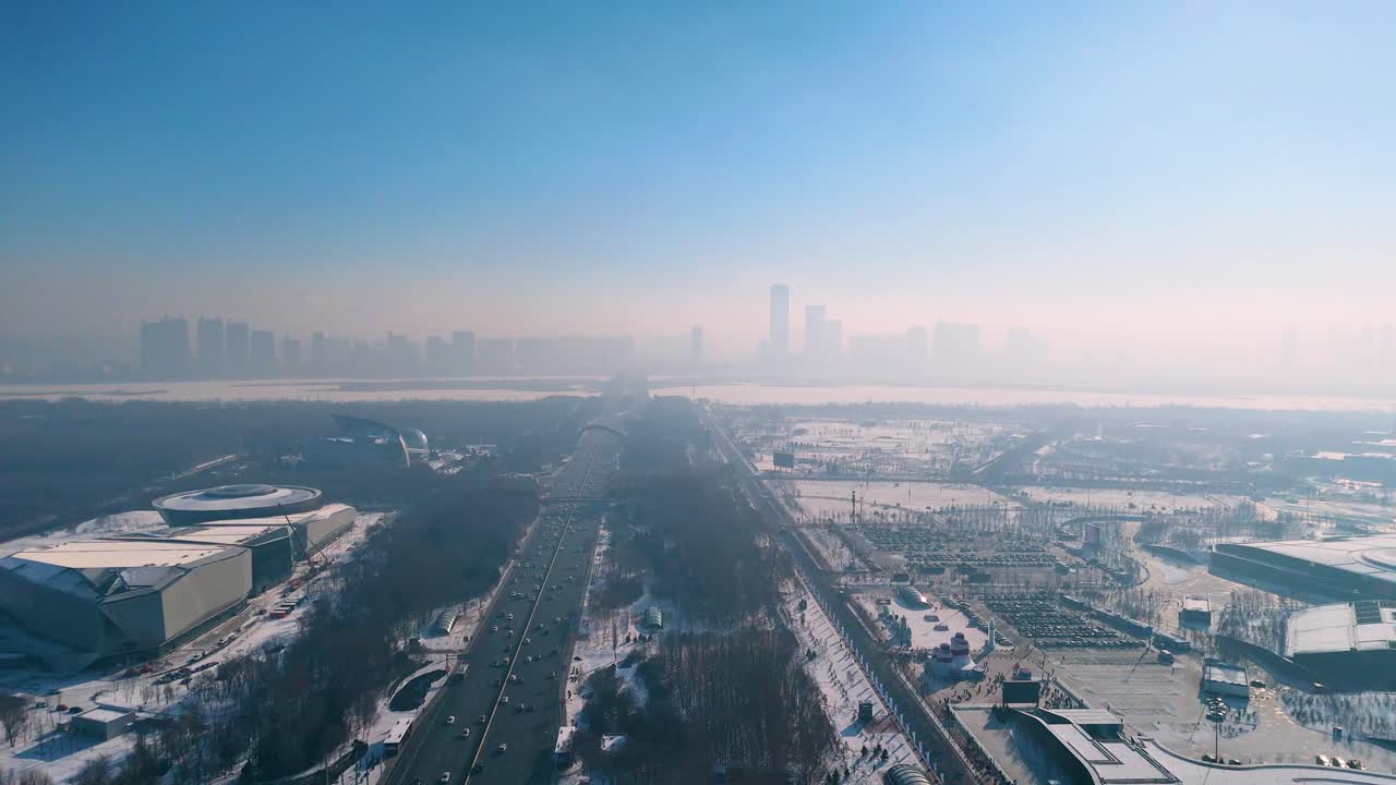 A smooth drone shot moves to the left while maintaining its angle, capturing the Harbin skyline during a crisp winter day. China