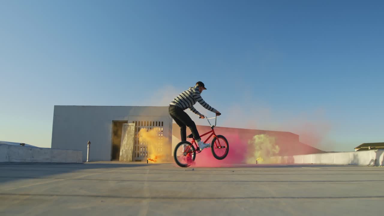 jinete de bmx en un techo saltando y usando granadas de humo
