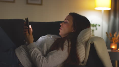 close up de una mujer acostada en el sofá en casa en streaming o viendo una película o un programa o desplazándose por internet en el teléfono móvil 8