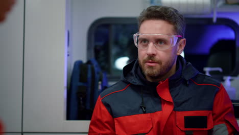 portrait of paramedic talking with colleague in ambulance car