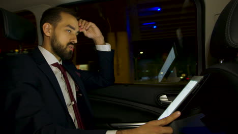 hombre de negocios con un traje de negocios en el asiento trasero de su coche de lujo