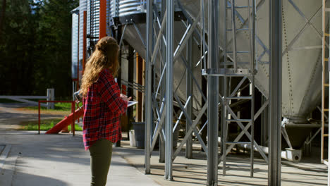 side view of caucasian female worker looking at storage tanks working on digital tablet 4k