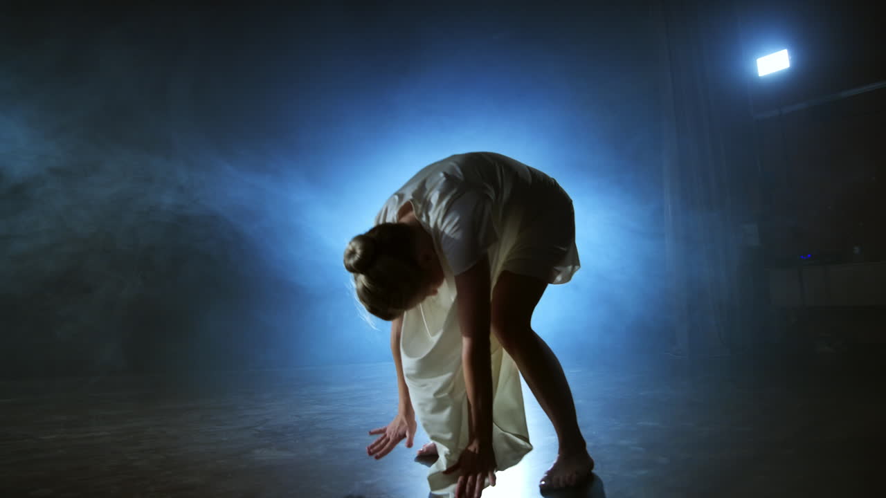 movimiento lento: bailarina en el escenario en el humo. ballet moderno descalzo en el escenario.