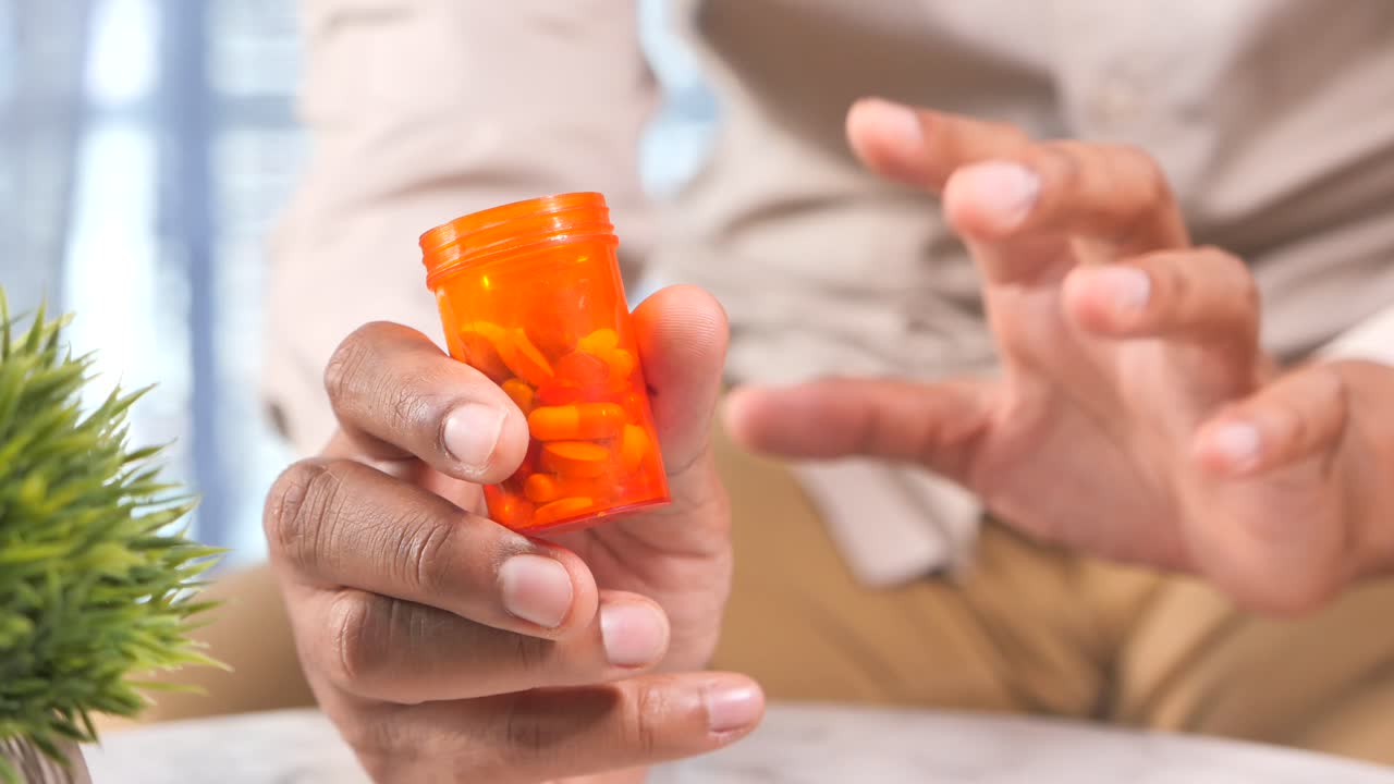 persona que sostiene una botella de pastillas