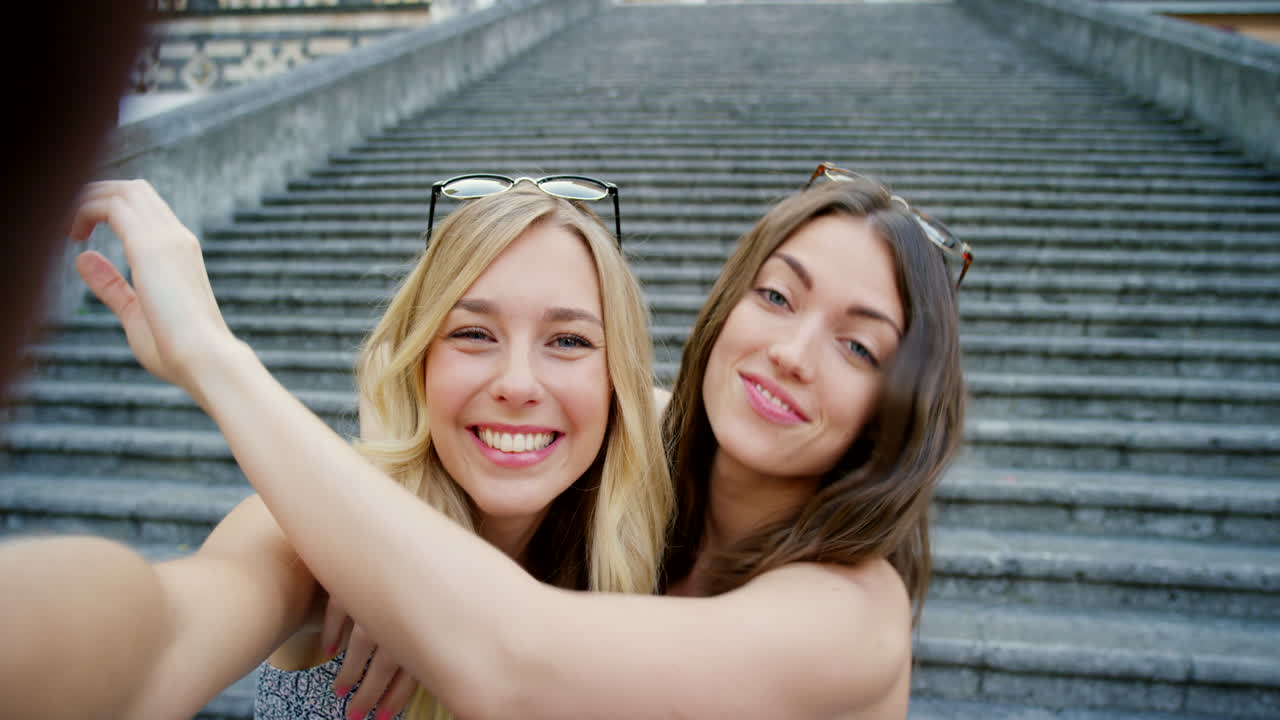 dos mujeres tomando una selfie en una escalera en una ciudad europea