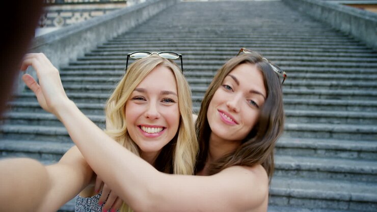 Due donne che si scattano un selfie su una scalinata in una città europea