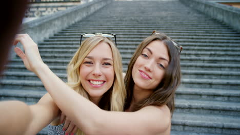 two women taking a selfie on a staircase in a european city