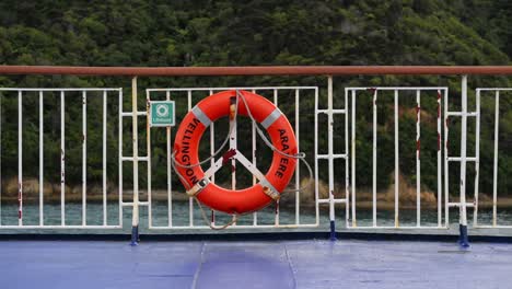 aro salvavidas en la baranda de un ferry con las exuberantes montañas costeras del marlborough sound en el fondo