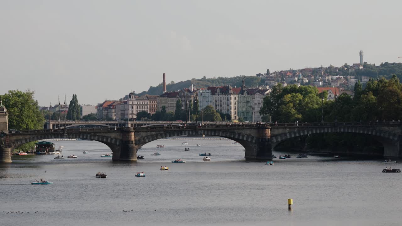 Wide view of the Legions Bridge crossing the Vltava River with boats and Prague’s historic skyline