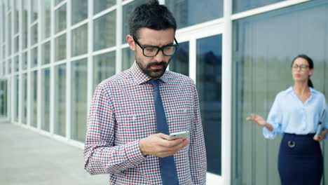 businessman using smartphone in front of office building