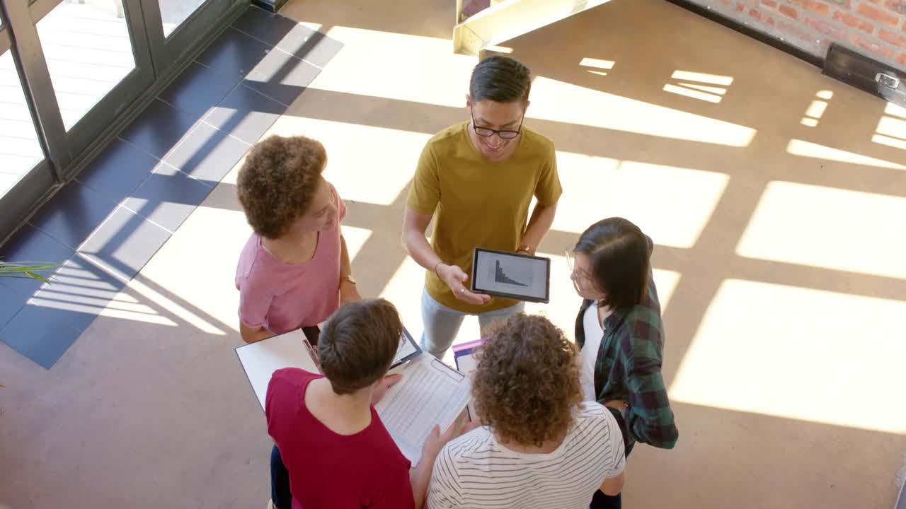 alto ángulo de cinco diversos colegas masculinos y femeninos en una discusión casual en el pasillo, cámara lenta