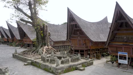 casas tradicionais batak com telhados elevados na ilha de samosir, lago toba, com as antigas pedras batu parsidangan em primeiro plano