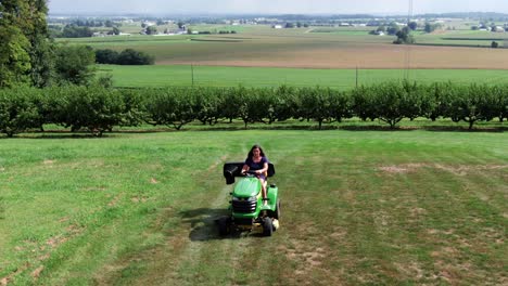 joven hispana cortando césped en cortadora de tractor