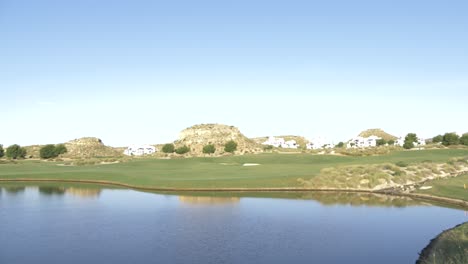 campo de golf con cielos azules y gran lago