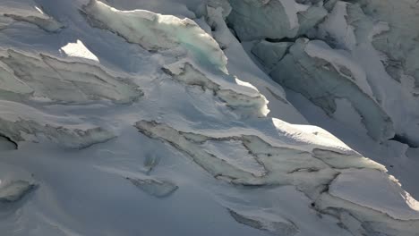 aerial-tilt-up:-blue-ice-of-a-glacier-in-the-swiss-alps,-sunny-day,-nature-landscape