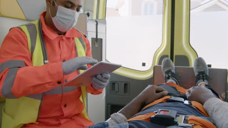 male paramedic with face mask using tablet computer while riding in an ambulance 2