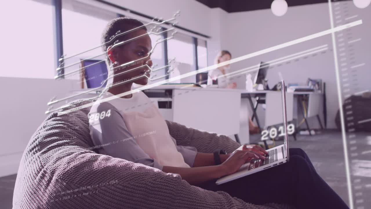 Woman typing on laptop by windows in office, causing line graphs sliding charting business growth