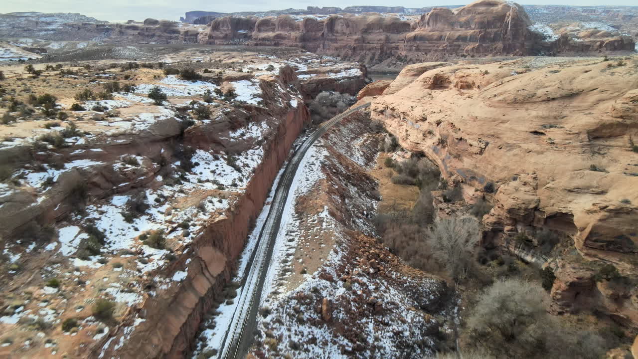 Ripresa con drone che segue una ferrovia mineraria verso il fiume Colorado tra le montagne di arenaria che circondano Moab, Utah.