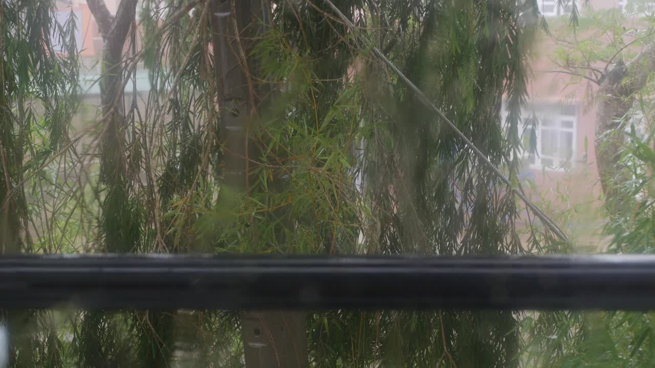 강한 물이 창문 유리창에 부히고 아래로 흘러내립니다. 근접 사진. 비가 오는 계절에 유리 바탕에 방울이 떨어집니다.