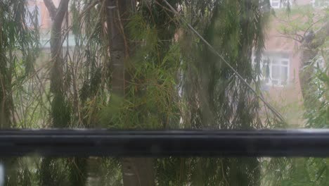 strong rain water flushes against window glass and streaming down. close-up. raindrops on glass background in rainy season. 4k