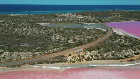 aerial view looking over the road and shoreline of pink lake, hutt lagoon, western australia