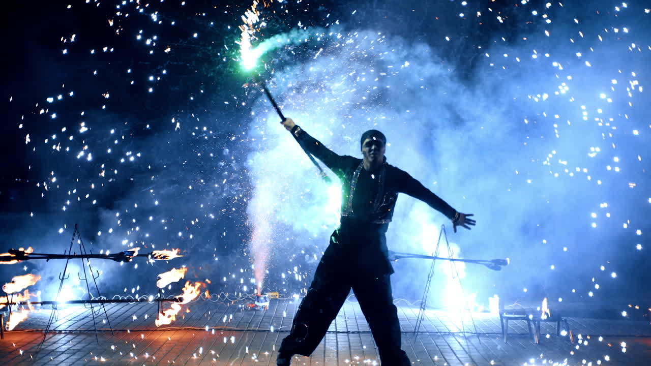 Bright firework show performed by male artist. Dancer moves rotating the stick producing sparks.