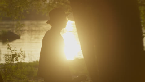 person walking along a riverbank at sunset