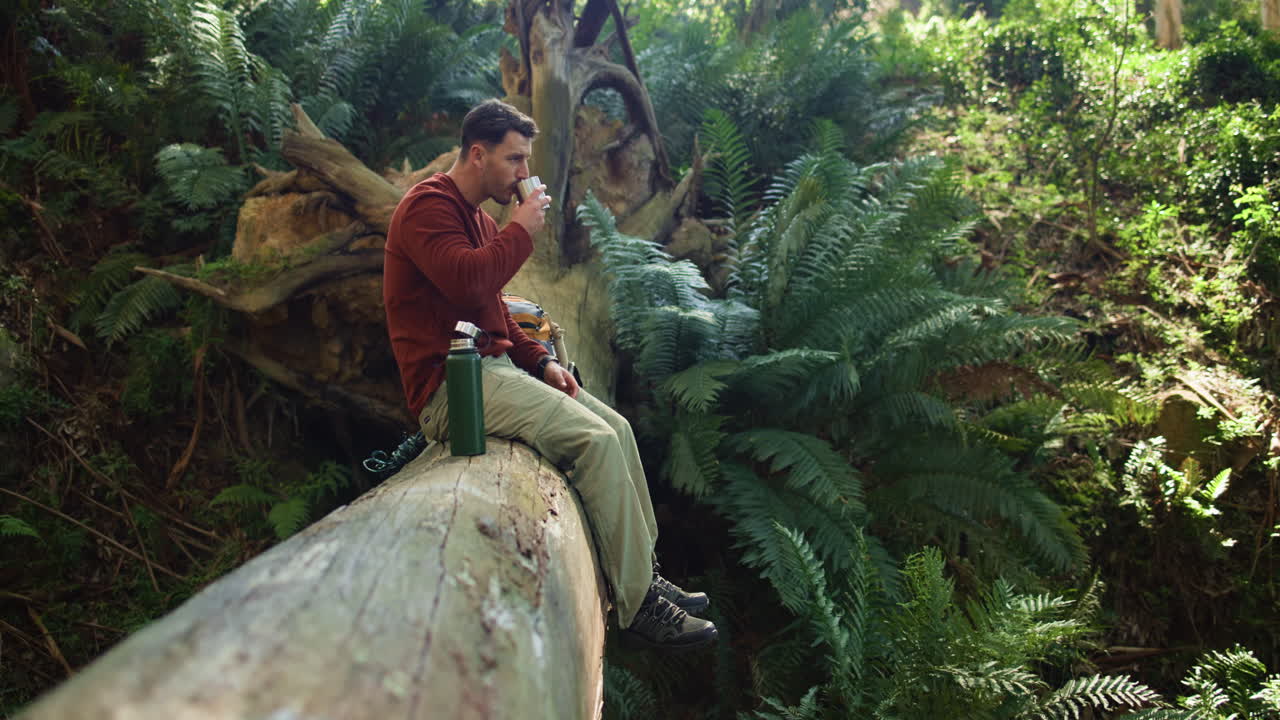 Man relaxing and drinking in a lush forest