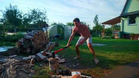 joven fuerte sosteniendo un hacha dividiendo un trozo de leña al aire libre en lituania