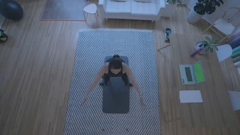 an overhead shot of a women doing stretches in front of a computer green screen at home in her living room