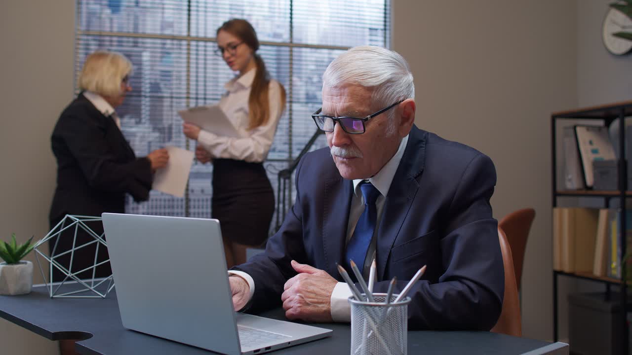 freelancer senior concentrado en el desarrollo de proyectos mientras trabaja, escribiendo en una computadora portátil en la oficina