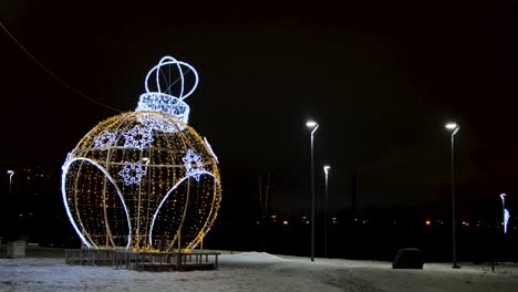 giant illuminated christmas ornament in a park at night