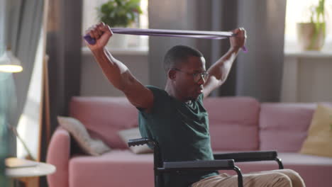 man in wheelchair doing resistance band exercises at home