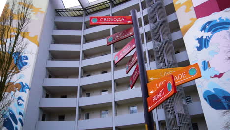 Close-up-shot-showing-freedom-street-signs-in-different-languages-in-front-of-colorful-building