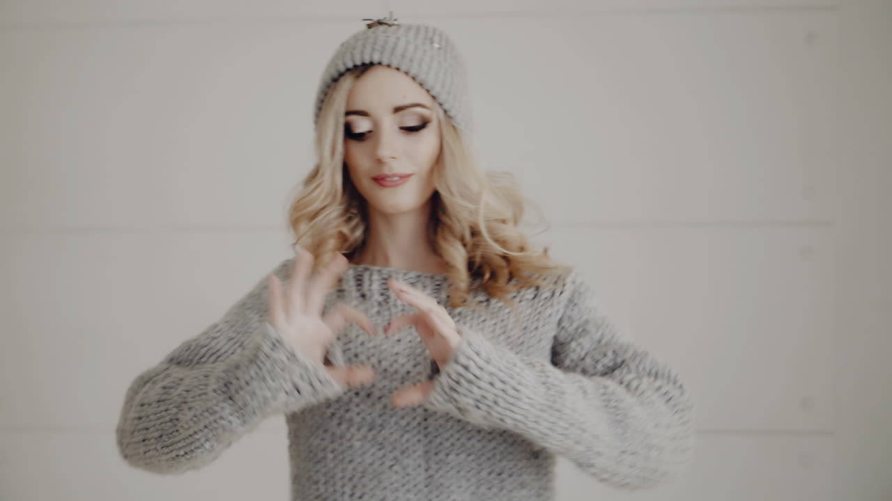 Woman showing heart shaped hands. Young attractive woman in black studio showing heart shaped hands