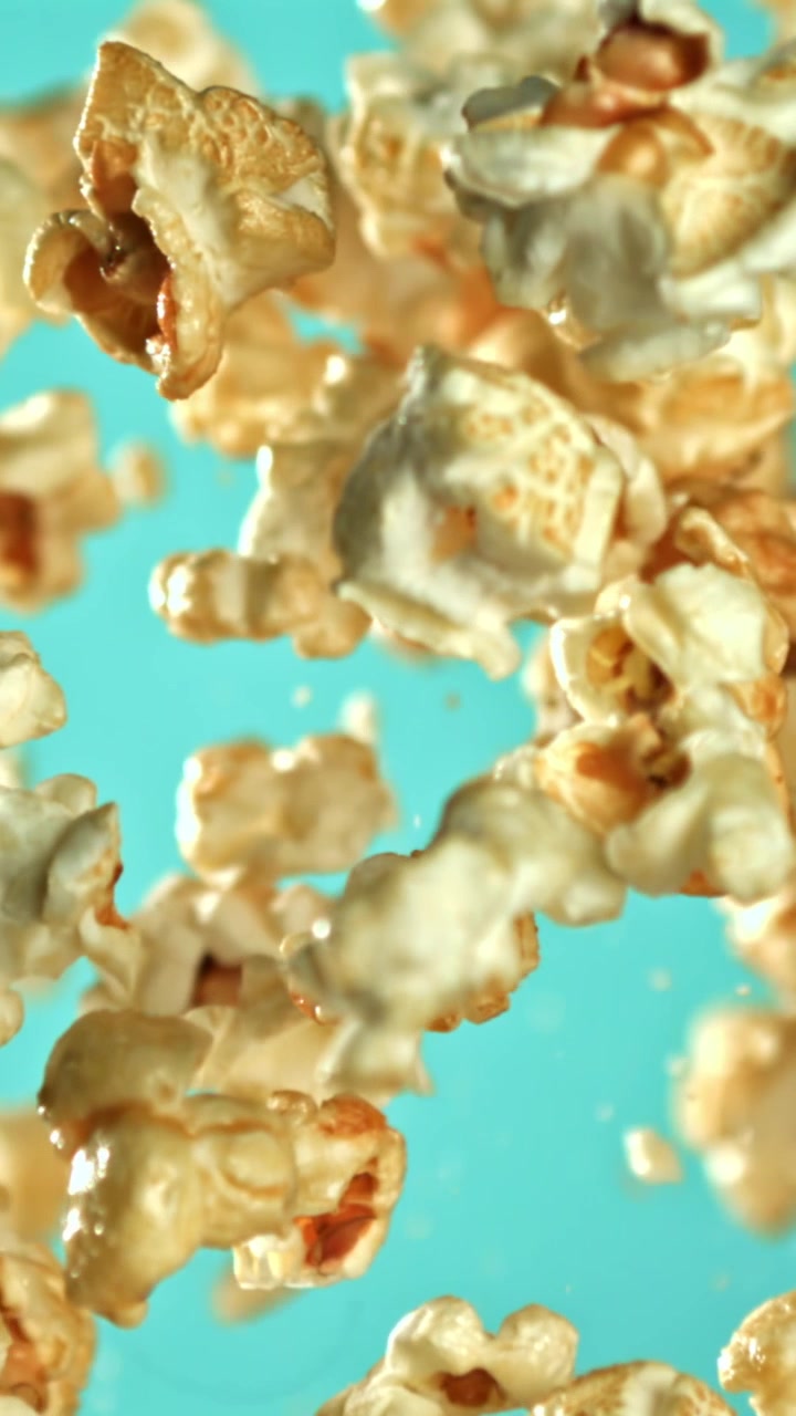 Popcorn che galleggiano al rallentatore su uno sfondo turchese vibrante