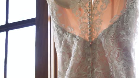 wedding gown rear close-up, pearl accents, beautiful white dress hangs in window