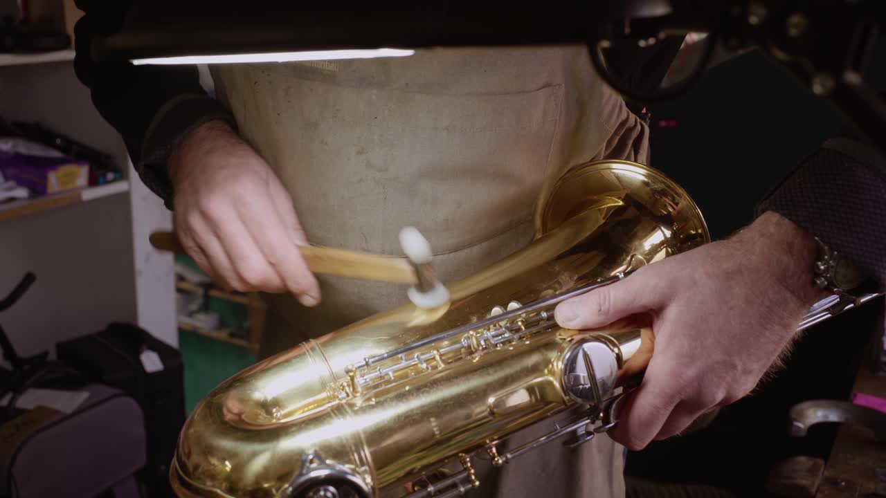 A craftsman performing maintenance on a saxophone in a workshop