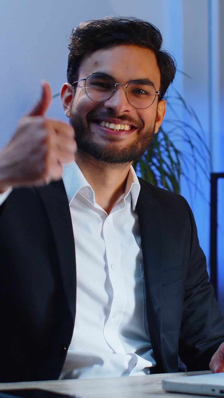 Happy business man looking approvingly at camera showing thumbs up like positive sign good news